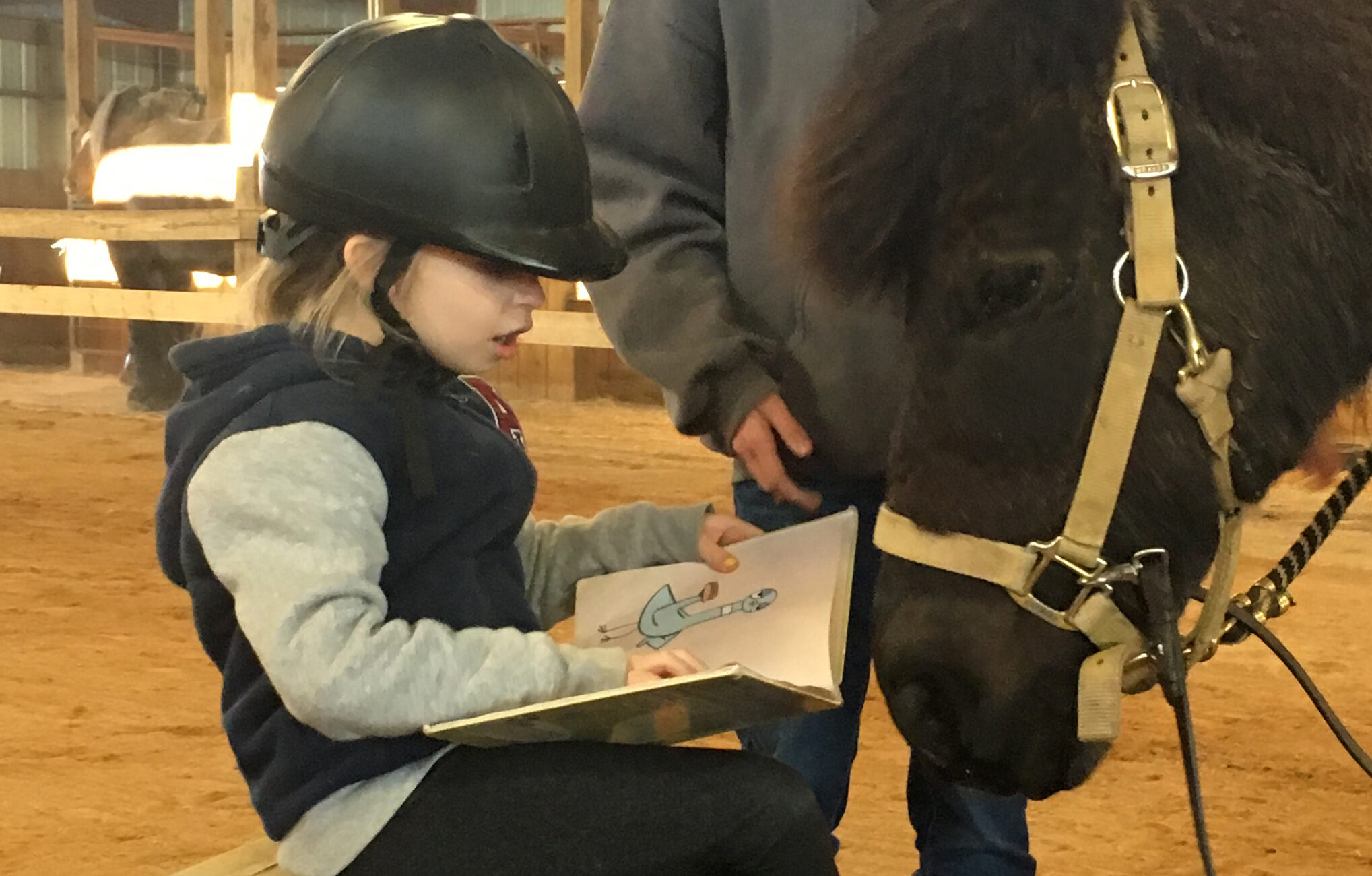 child reading to a black pony